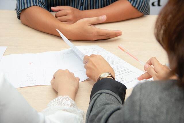 two people reviewing a lease as someone else oversees it